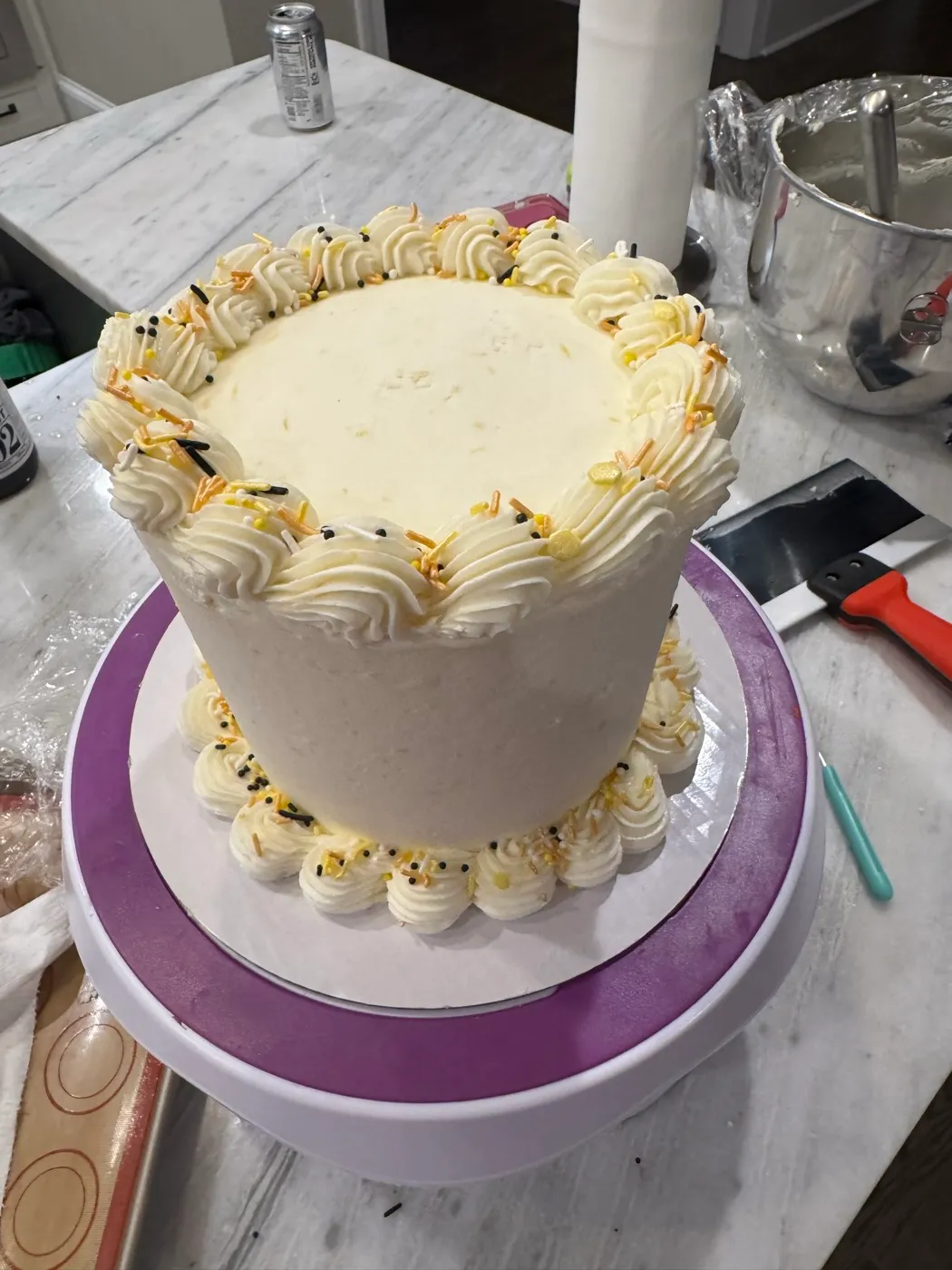 A vanilla cake being finished by hand on the decorating turntable